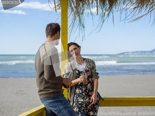 Image of young couple drinking beer together at the beach