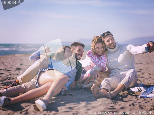 Image of Group of friends having fun on beach during autumn day