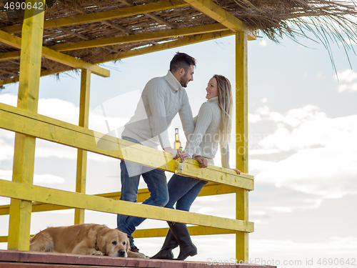 Image of young couple drinking beer together at the beach