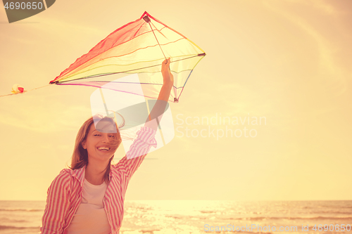 Image of Young Woman with kite at beach on autumn day