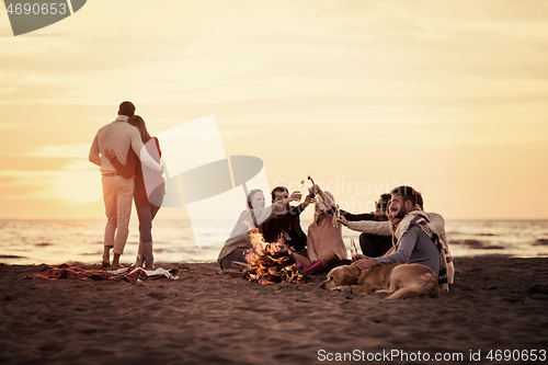 Image of Couple enjoying with friends at sunset on the beach