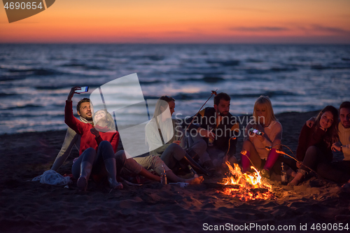 Image of a group of friends enjoying bonfire on beach