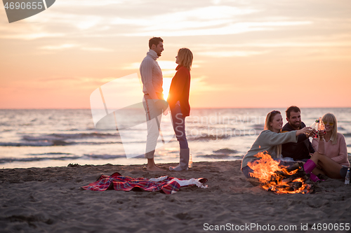 Image of Couple enjoying with friends at sunset on the beach