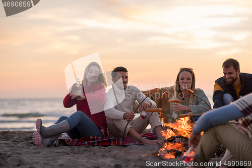 Image of Group Of Young Friends Sitting By The Fire at beach