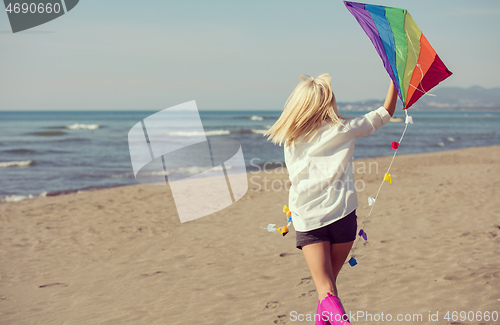 Image of Young Woman with kite at beach on autumn day