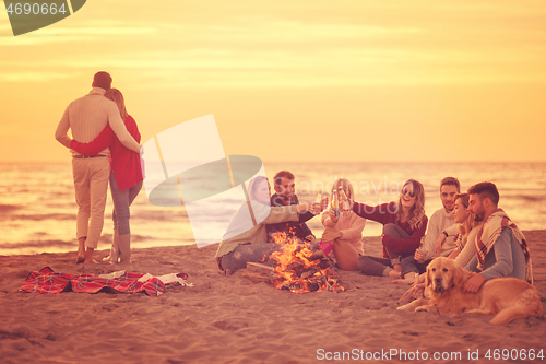 Image of Couple enjoying with friends at sunset on the beach