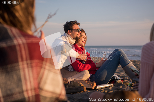 Image of Couple enjoying with friends at sunset on the beach