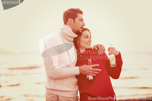 Image of Couple hugging and drinking beer together at the beach