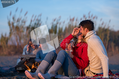 Image of Couple enjoying with friends at sunset on the beach