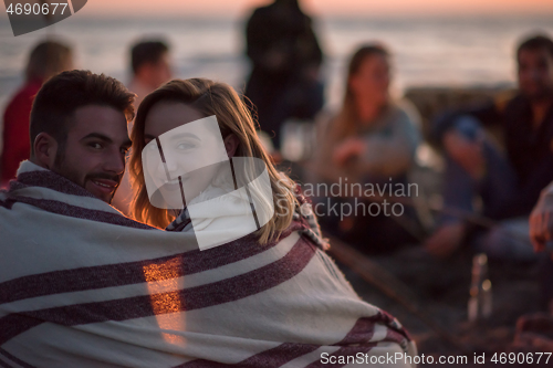 Image of Couple enjoying with friends at sunset on the beach