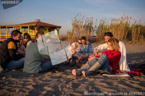 Image of Couple enjoying with friends at sunset on the beach