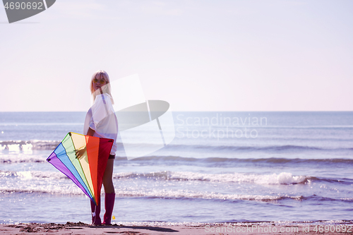 Image of Young Woman with kite at beach on autumn day