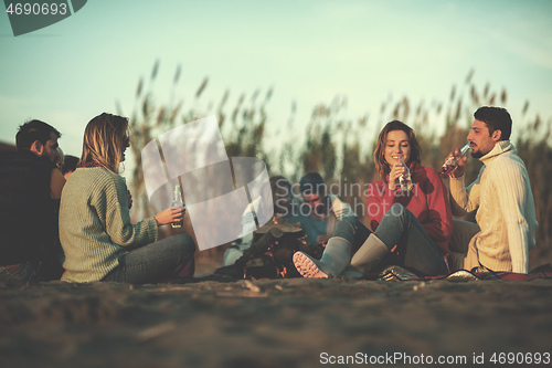 Image of Couple enjoying with friends at sunset on the beach