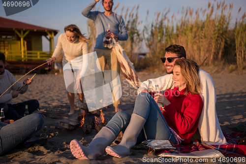 Image of Couple enjoying with friends at sunset on the beach