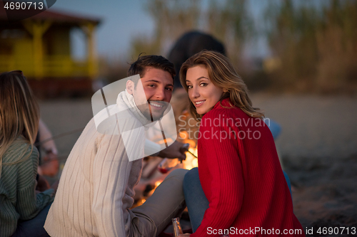 Image of Couple enjoying with friends at sunset on the beach