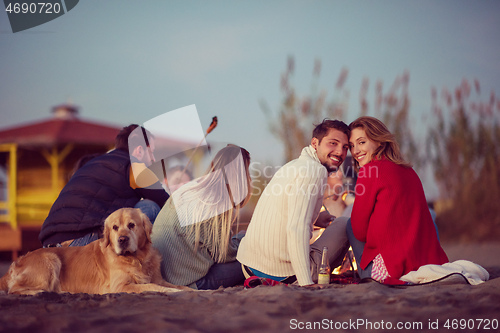 Image of Couple enjoying with friends at sunset on the beach