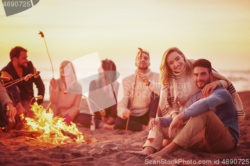 Image of Group Of Young Friends Sitting By The Fire at beach