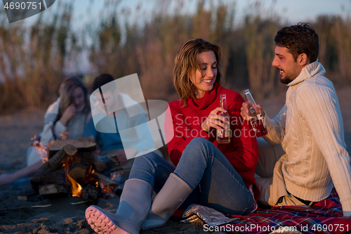 Image of Couple enjoying with friends at sunset on the beach