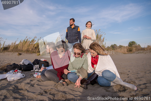 Image of Friends having fun at beach on autumn day