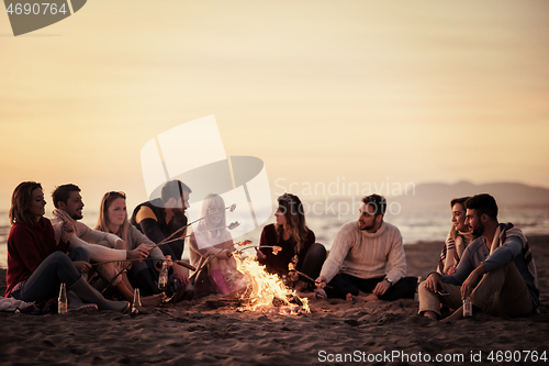 Image of Group Of Young Friends Sitting By The Fire at beach