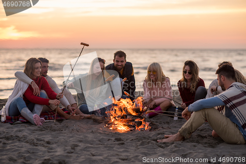 Image of Group Of Young Friends Sitting By The Fire at beach