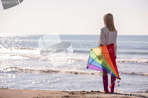 Image of Young Woman with kite at beach on autumn day