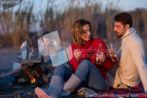 Image of Couple enjoying with friends at sunset on the beach