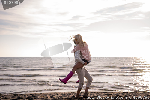 Image of Loving young couple on a beach at autumn sunny day