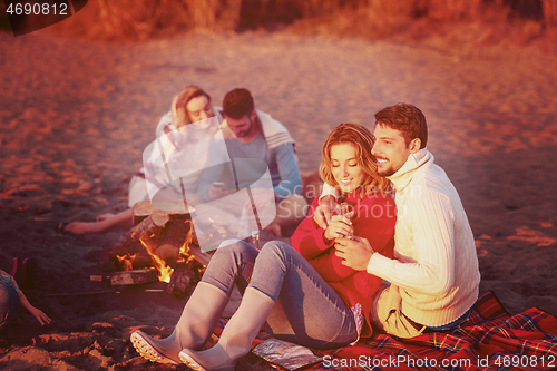 Image of Couple enjoying with friends at sunset on the beach