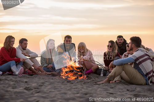 Image of Group Of Young Friends Sitting By The Fire at beach