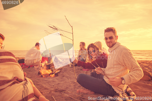 Image of Couple enjoying with friends at sunset on the beach