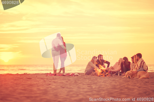 Image of Couple enjoying with friends at sunset on the beach