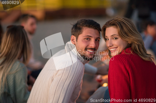 Image of Couple enjoying with friends at sunset on the beach