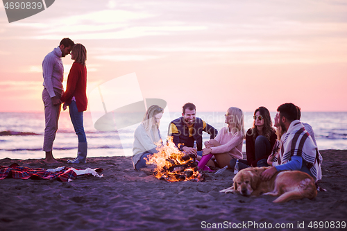 Image of Couple enjoying with friends at sunset on the beach