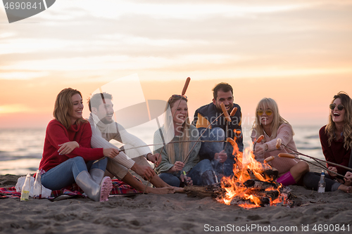 Image of Group Of Young Friends Sitting By The Fire at beach