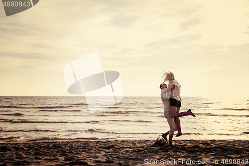 Image of Loving young couple on a beach at autumn sunny day