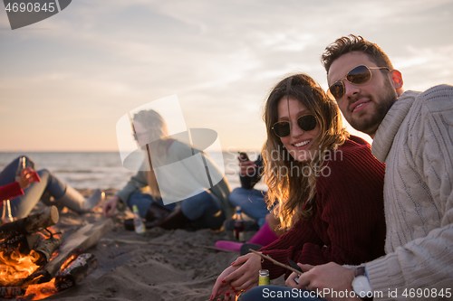 Image of Couple enjoying with friends at sunset on the beach