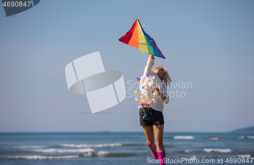 Image of Young Woman with kite at beach on autumn day