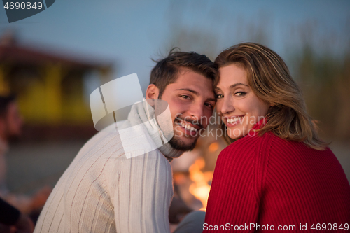 Image of Couple enjoying with friends at sunset on the beach