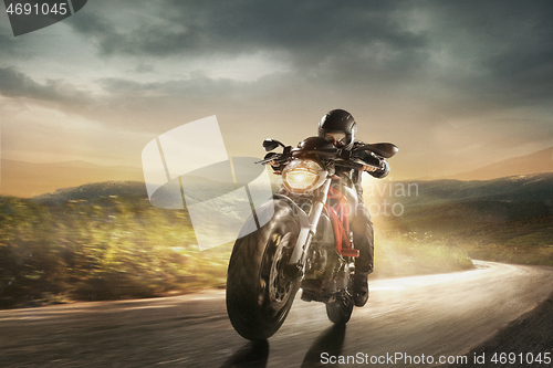 Image of Motorcyclist in black helmet driving motorbike