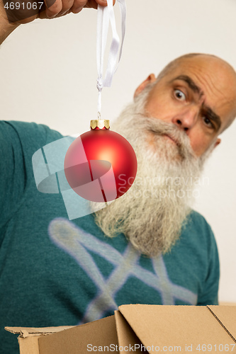 Image of bearded man looking at red christmas ball