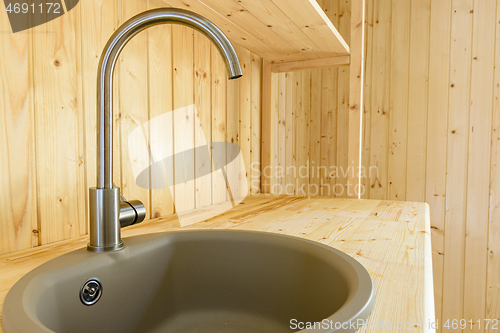 Image of Sink with a mixer close-up in a kitchen set made of natural wood