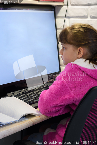 Image of A girl studies at a computer with a large monitor, view from the