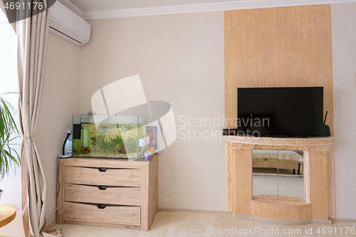 Image of A corner in the room, there is an aquarium, an air conditioner hangs and a stylized place for a TV