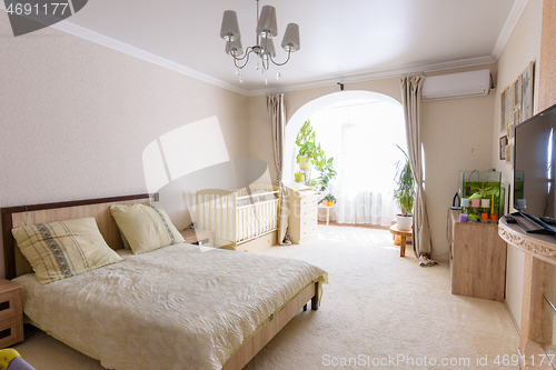 Image of Nice interior of a bedroom combined with a balcony and a crib for a newborn baby