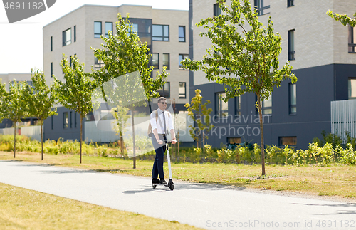 Image of businessman with backpack riding electric scooter