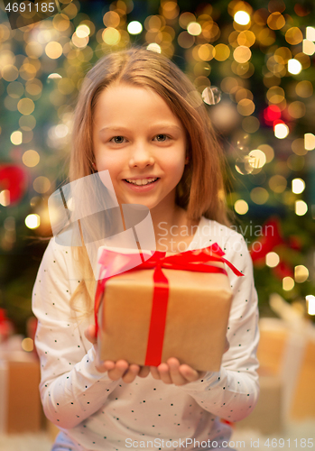 Image of smiling girl with christmas gift at home