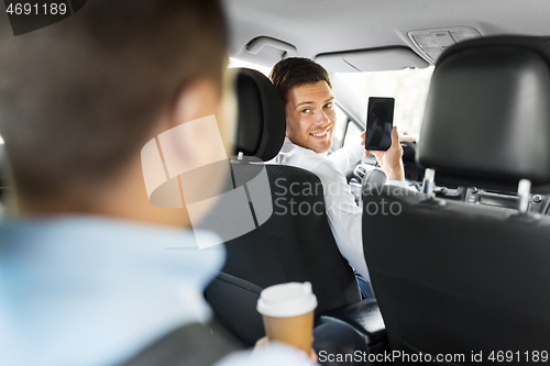 Image of car driver showing smartphone to male passenger