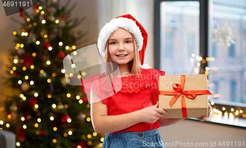 Image of girl in santa hat with christmas gift at home