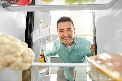 Image of man looking for food in fridge at kitchen